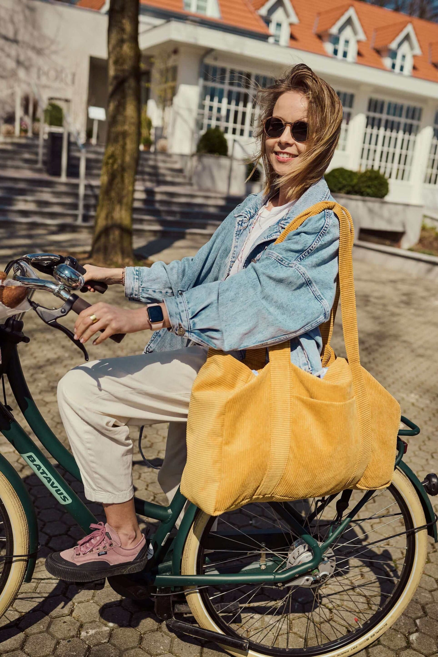 Woman on bicykle with corduroy shopper bag in yellow. Mom bag. Tote bag