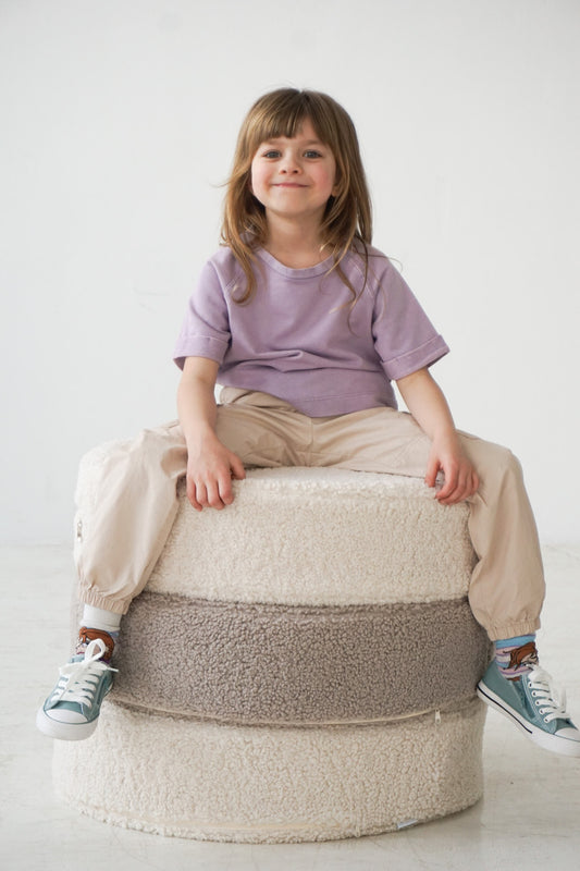 girl sitting on large boucle pouf by bettys home in taupe colour 
