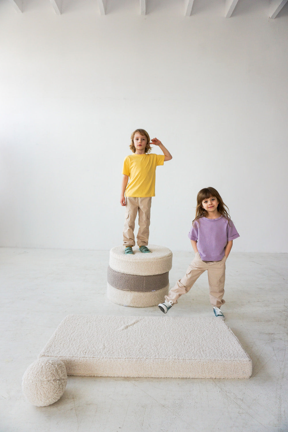 two kids standing on boucle pouf boy bettys home next to boucle mattress 