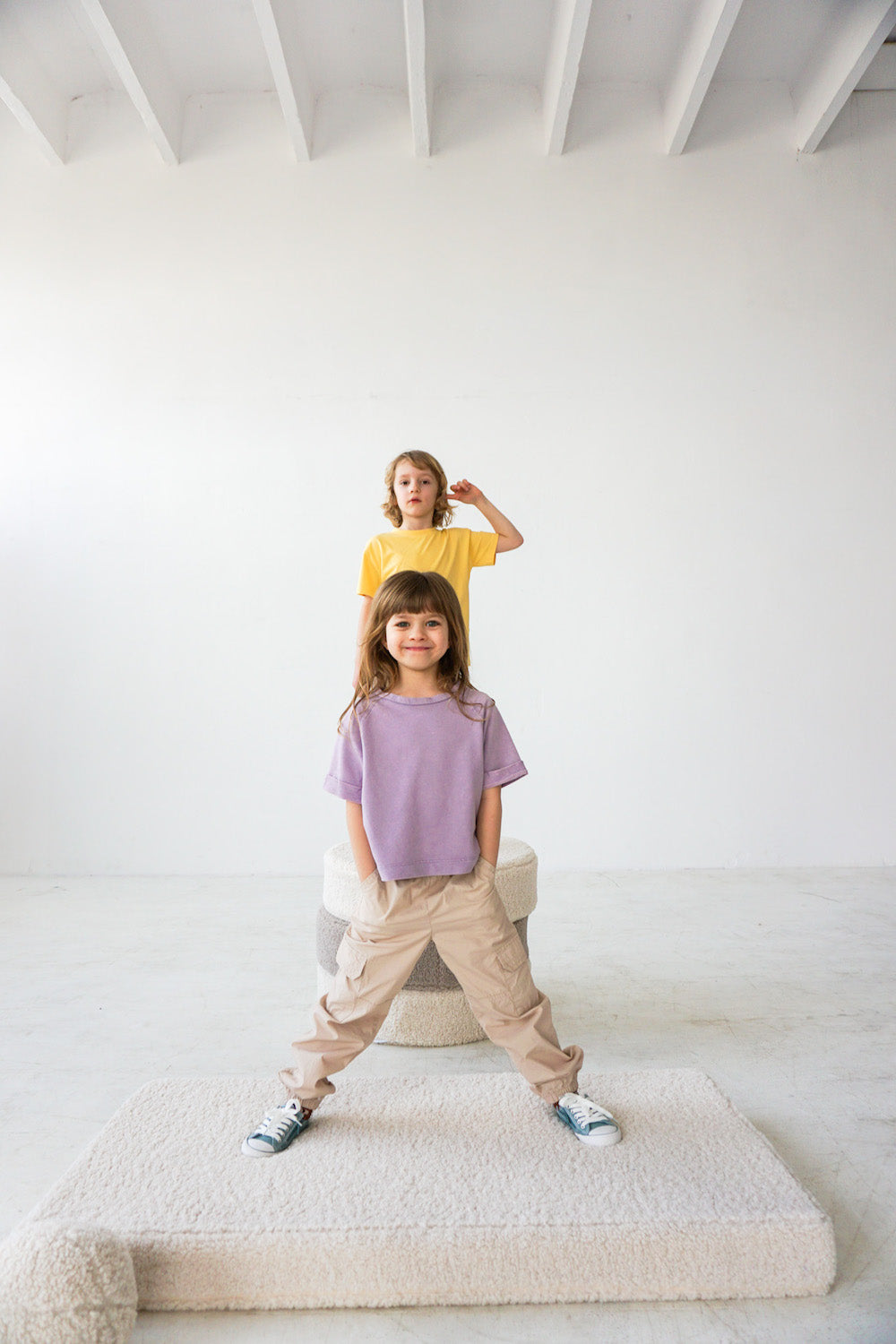two kids standing on boucle pouf boy bettys home next to boucle mattress and boucle ball