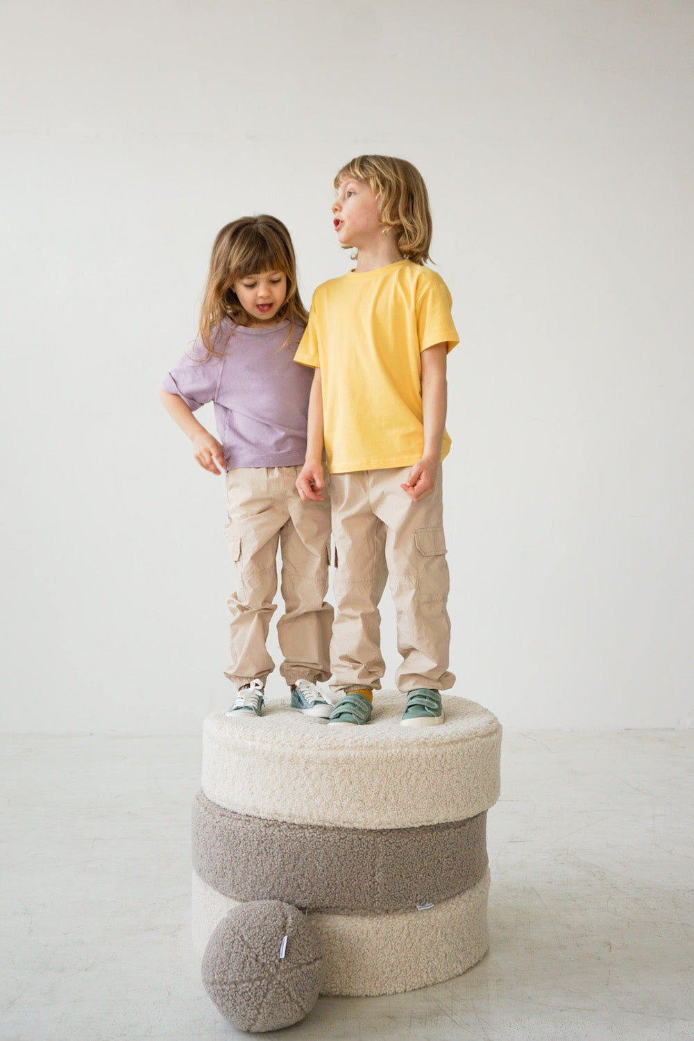 boy and girl standing on large boucle poufs by bettys home