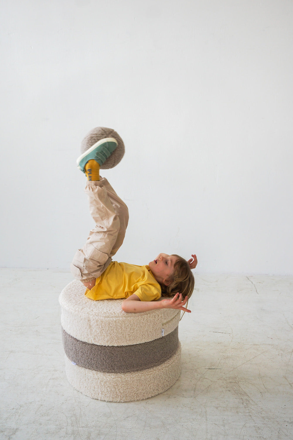 little boy playing on boucle pouf with boucle ball by bettys home in his legs 3