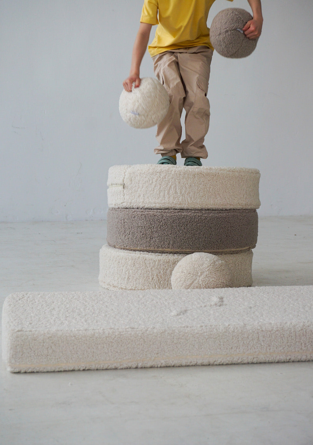 boy standing on boucle poufs by bettys home with boucle ball in hands