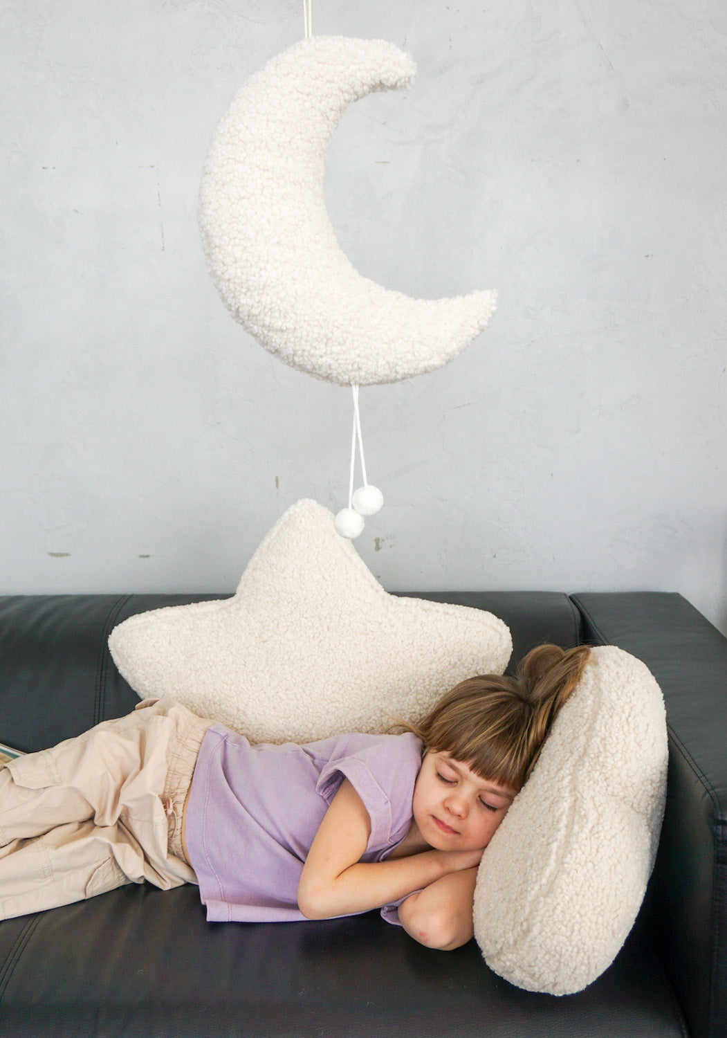 girl on couch with boucle moon pendant, boucle star cushion and boucle cloud