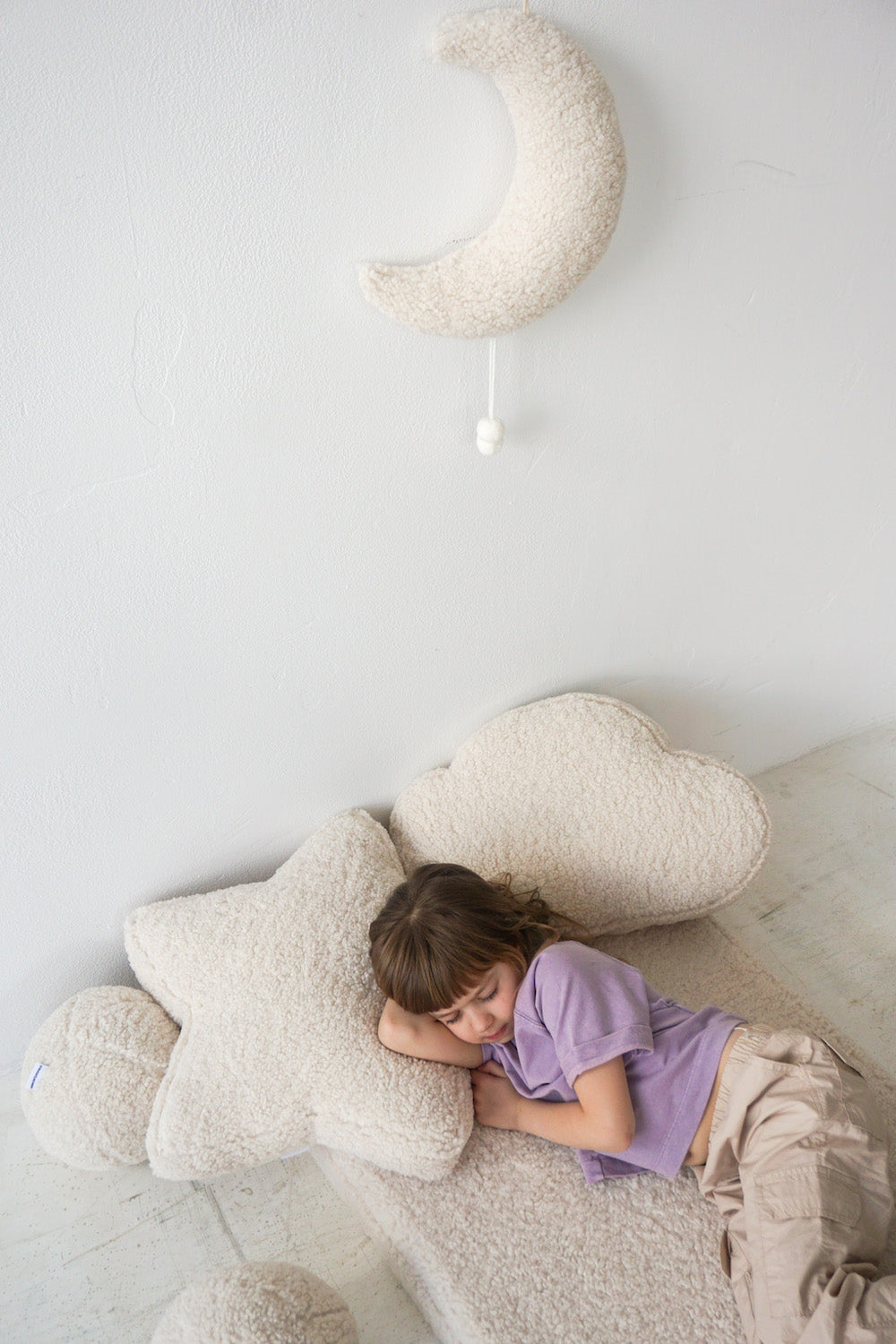 little girl sleeping on boucle mattress on boucle star cushion under head 