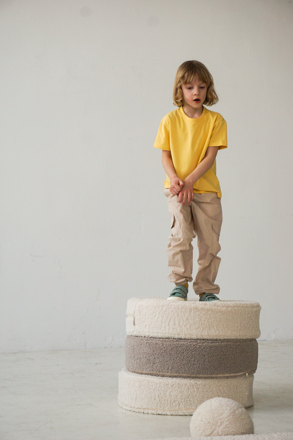 a boy standing on large boucle poufs by bettys home 4