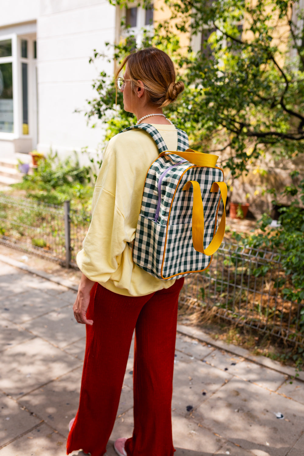 Woman with green gingham backpack by bettys home on her walk in city 