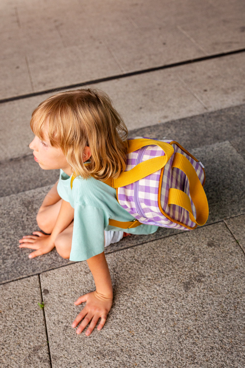 little boy sitting on stairs with small checkered backpack for kindergarten by bettys home 