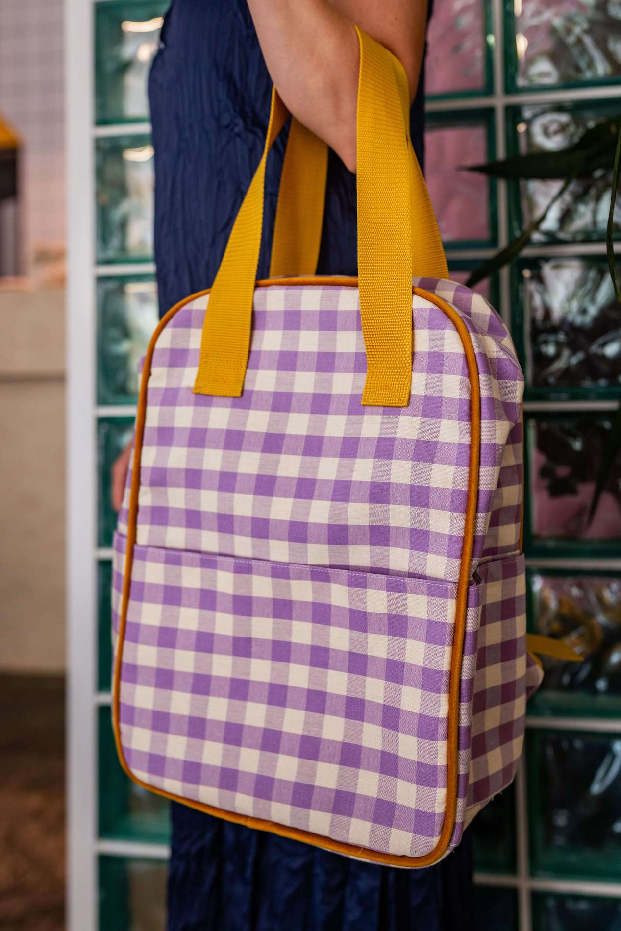 woman in restaurant wit checkered backpack in lilac on her hand. Gingham backpack by bettys home. Retro backpack 