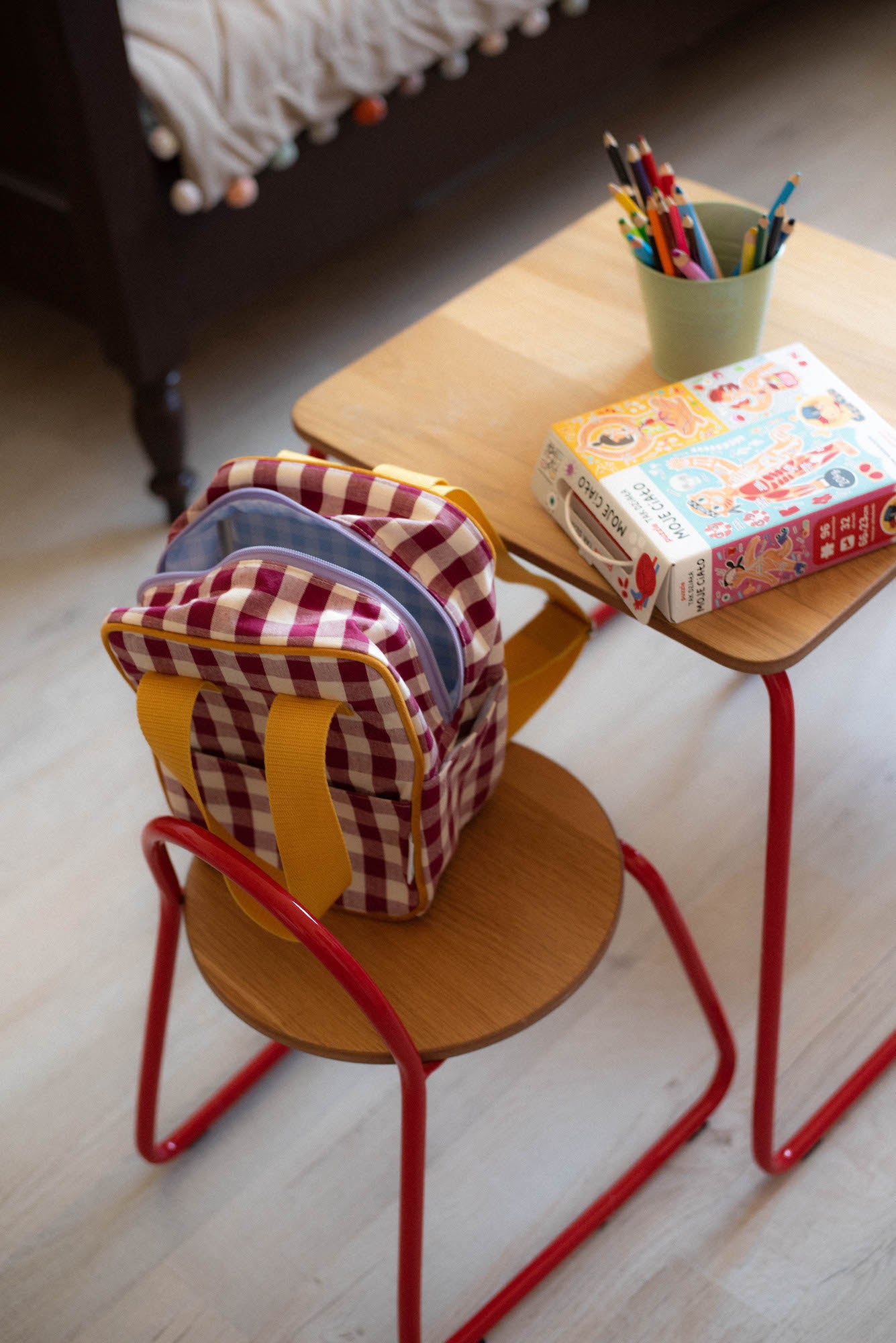 Small Red Gingham Backpack standing on a child's chair at a small table 