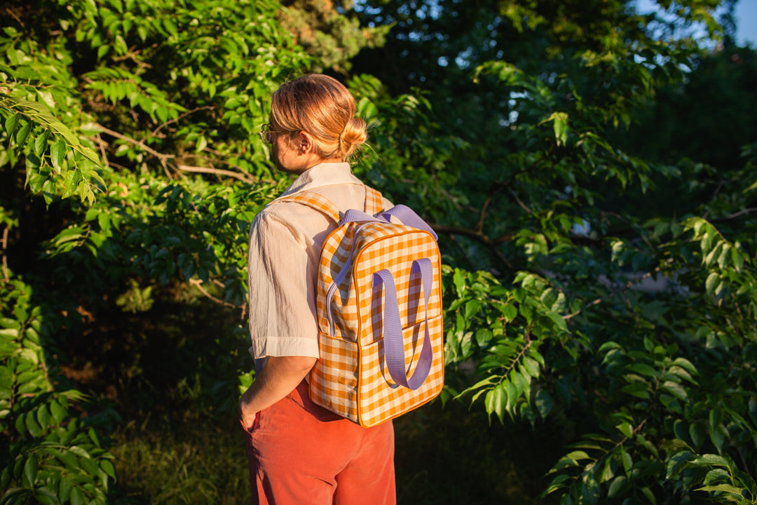 woman at front of trees with yellow checkered backpack by bettys home. gingham retro backpack