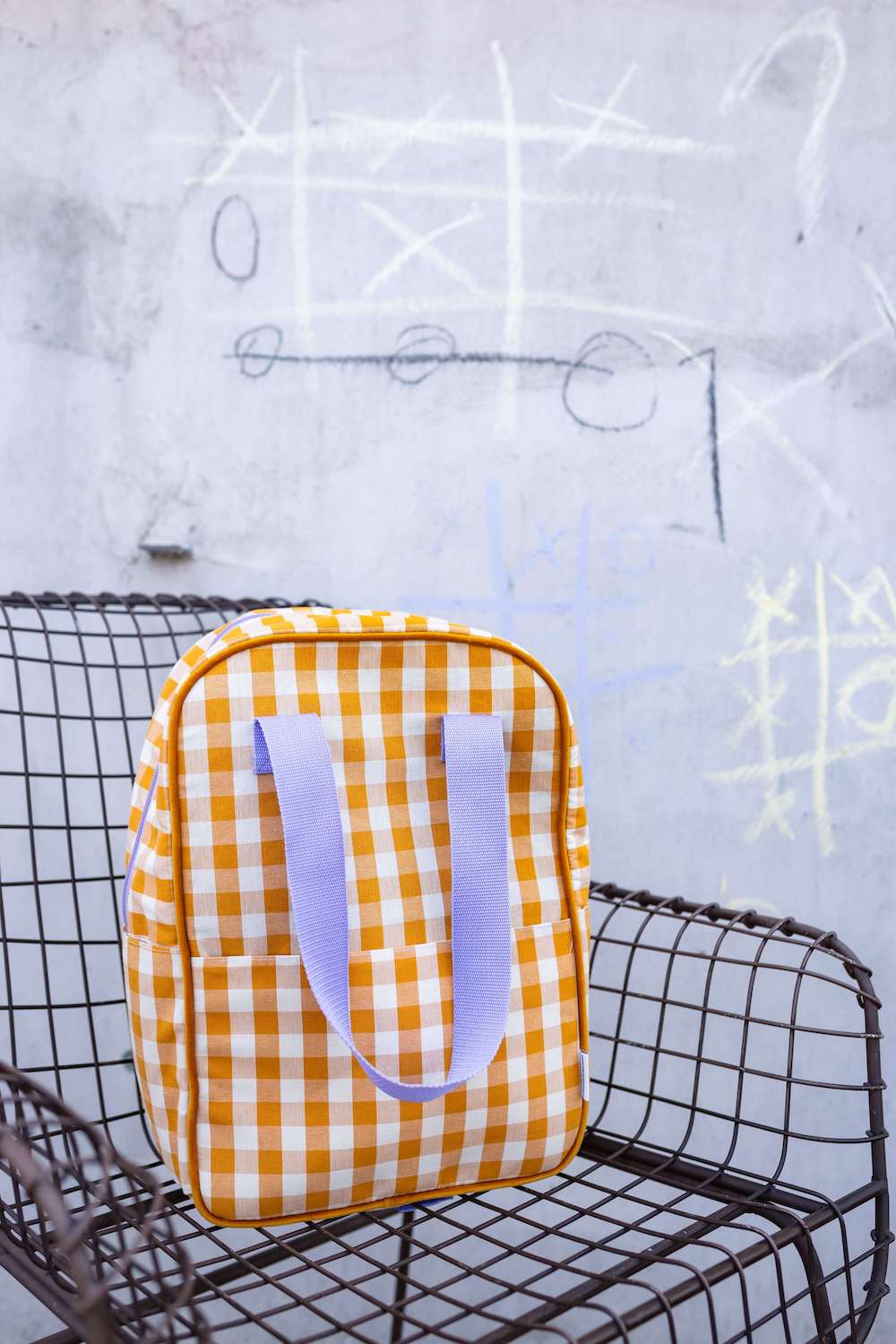 yellow gingham backpack with lilac belt on solid chair. Checkered retro backpack 