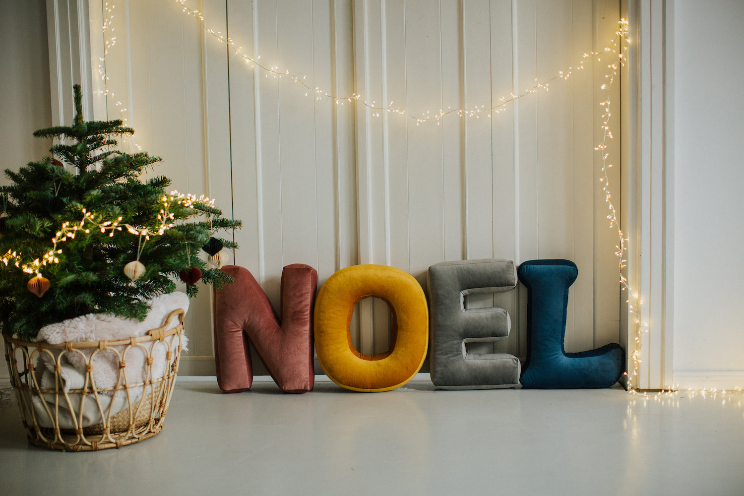 Velvet letter cushions from bettys home arranged in the word NOEL next to the Christmas tree 