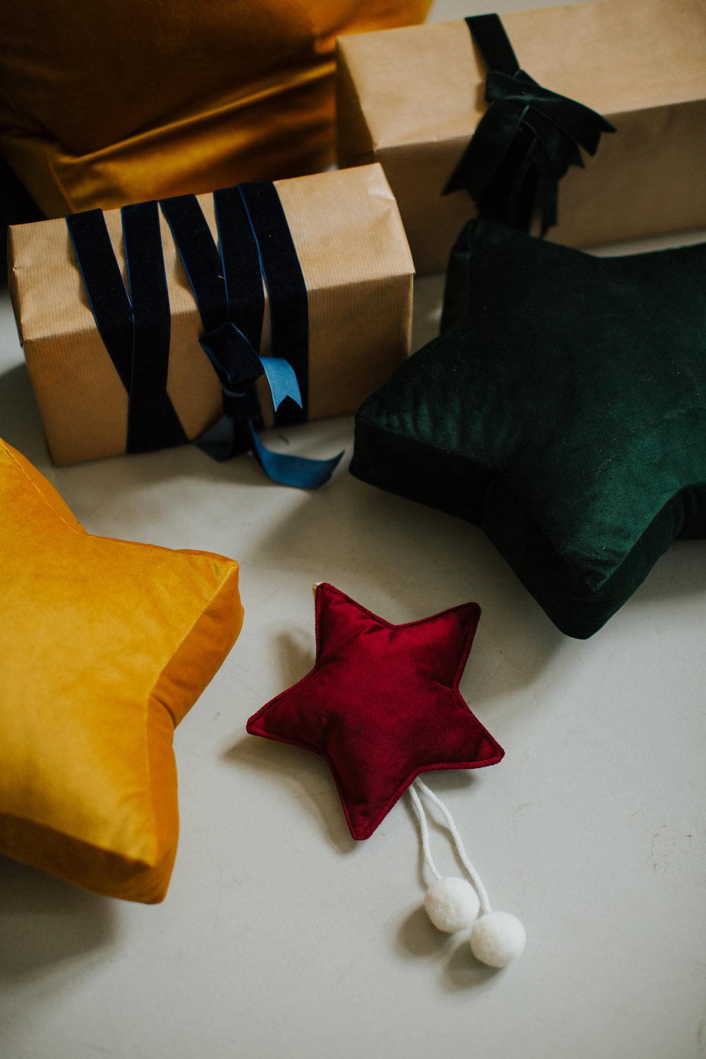Christmas velvet stars in green, yellow and wine next to christmas presents. Christmas gifts by Bettys Home