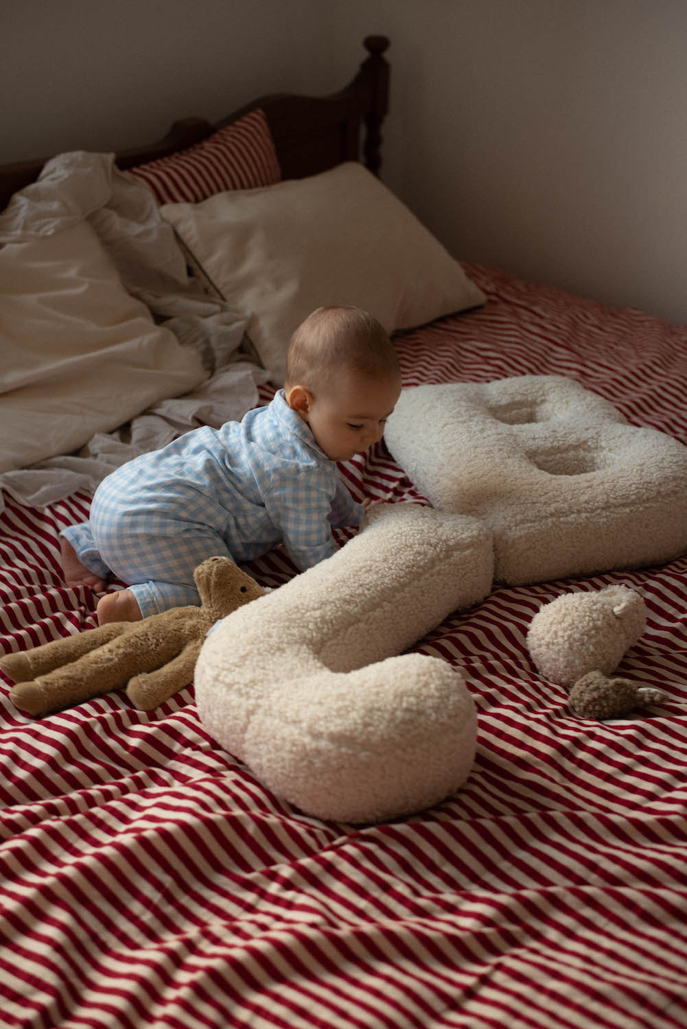 baby boy on bed in bedroom playing next to Boucle letter cushion J and B teddy letter pillow by bettys home