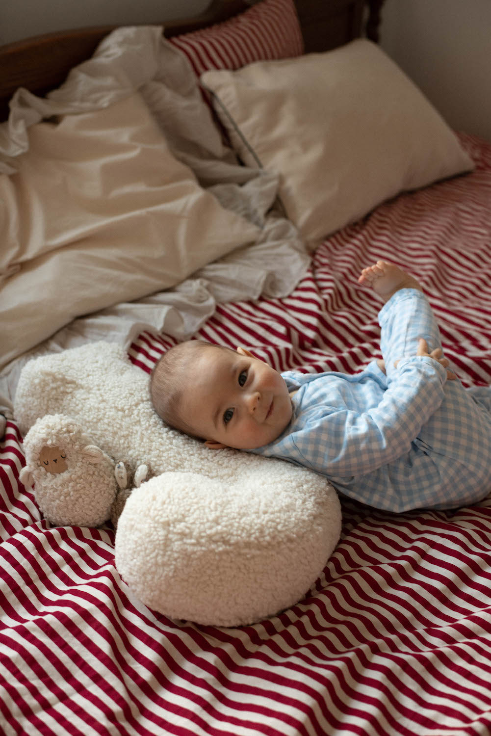 little baby boy lying on boucle letter cushion J in his bed
