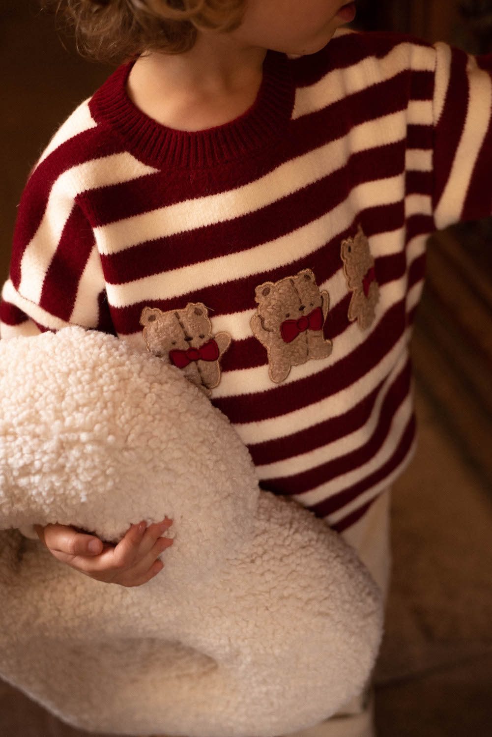 little boy in red stripes sweater holding teddy letter pillow B in his hands 