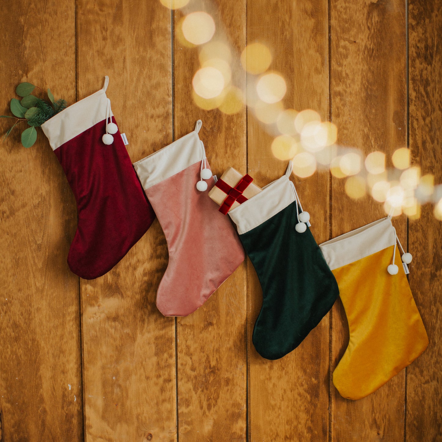 Four christmas stockings in velvet by Bettys Home hanging on a wooden wall as elegant christmas wall decorations