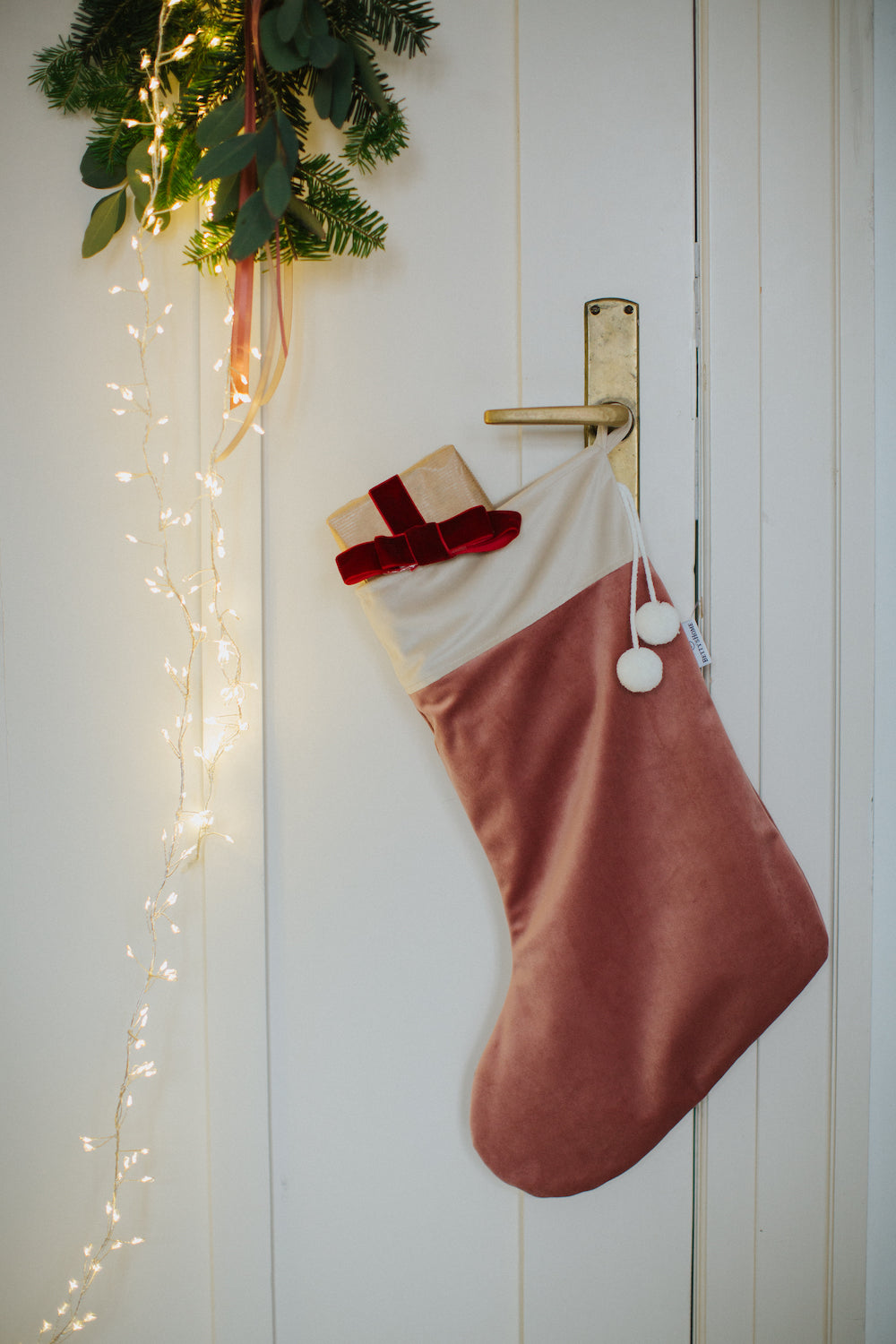 Christmas stocking pink by Bettys Home Hanging on a door handle with a small gift sticking out of the stocking