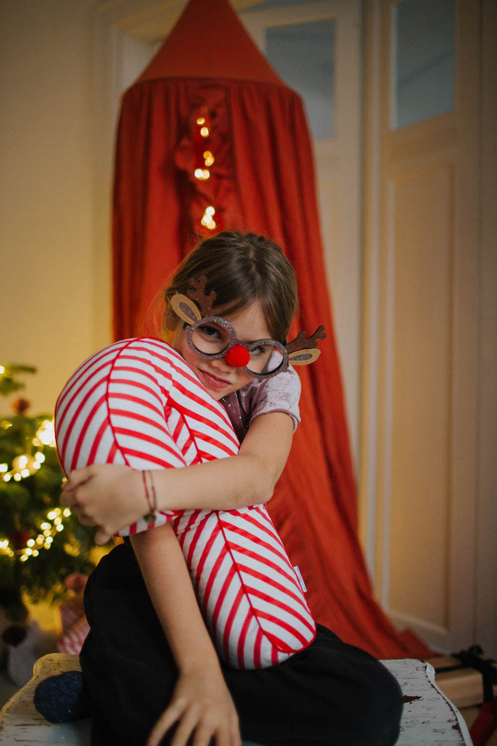 Christmas candy cane cushion red stripes by bettys home held by a little girl with Christmas glasses 