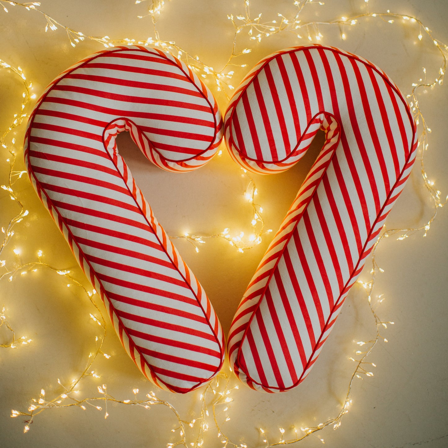 Christmas candy cane cushion red stripes by bettys home arranged in the shape of a heart among the Christmas lights