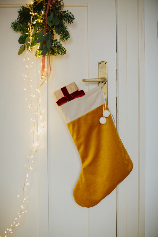 christmas stocking in yellow hanging on a door handle with small gift inside. elegant christmas door decorations