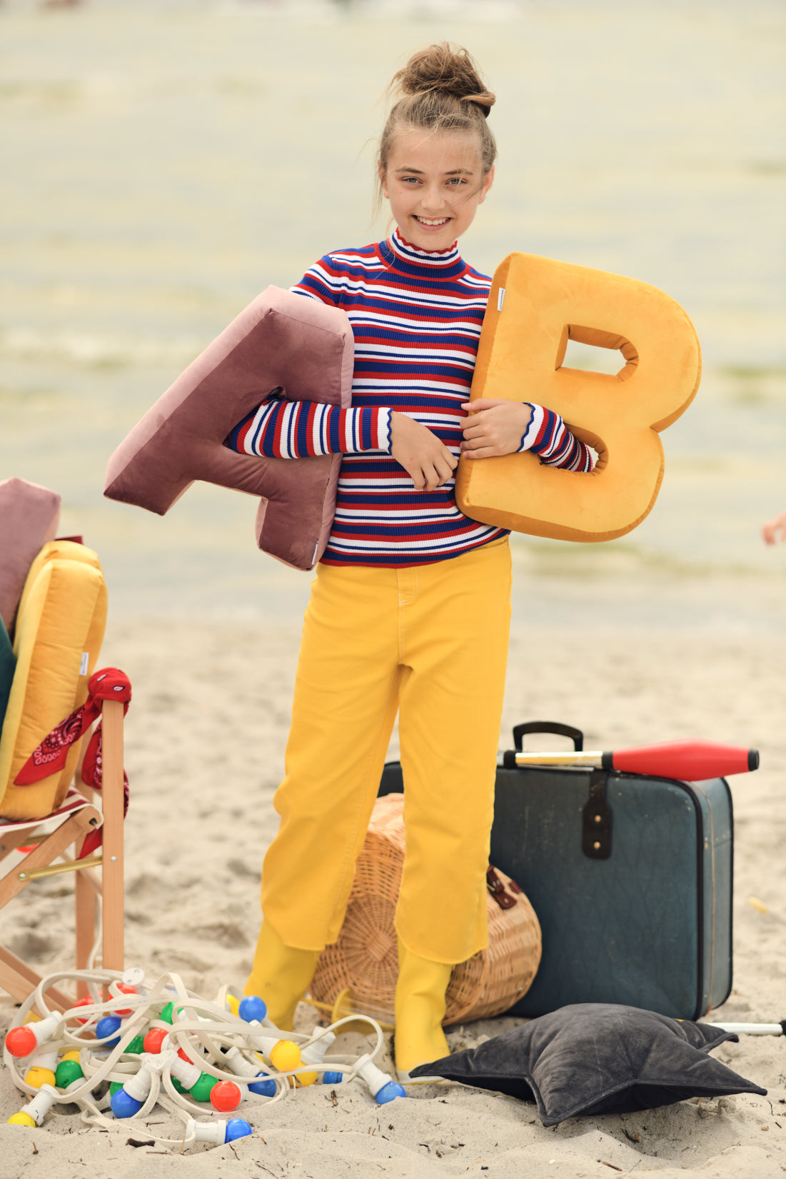 cute girl with velvet letter b yellow by bettys home standing on beach 