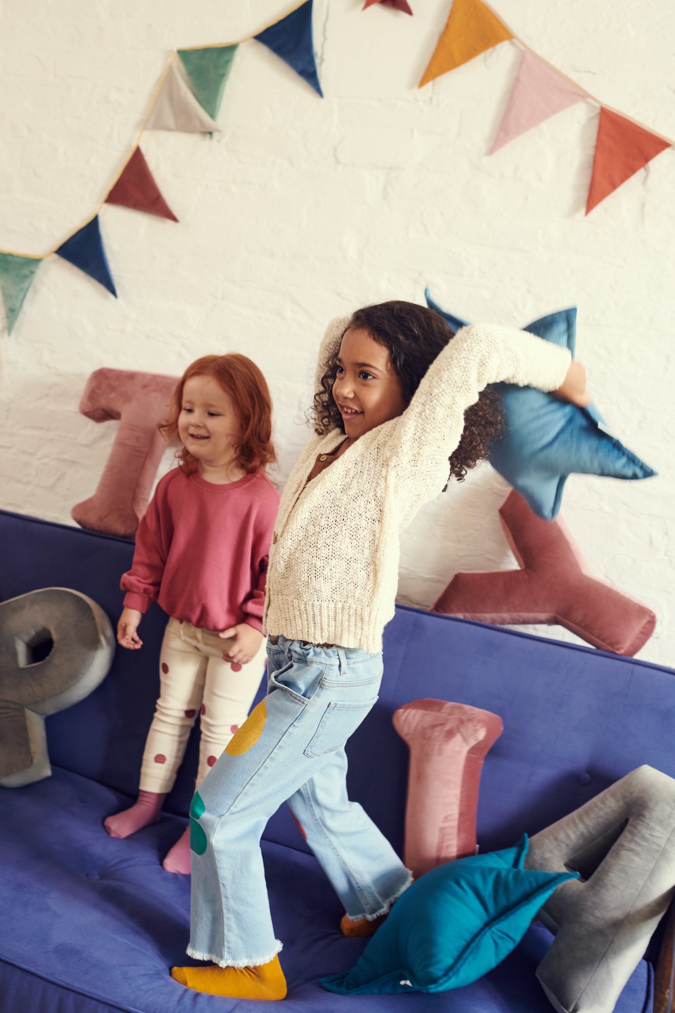 girls playing in nice decorate room with velvet star cushions by bettys home and velvet garland behind them