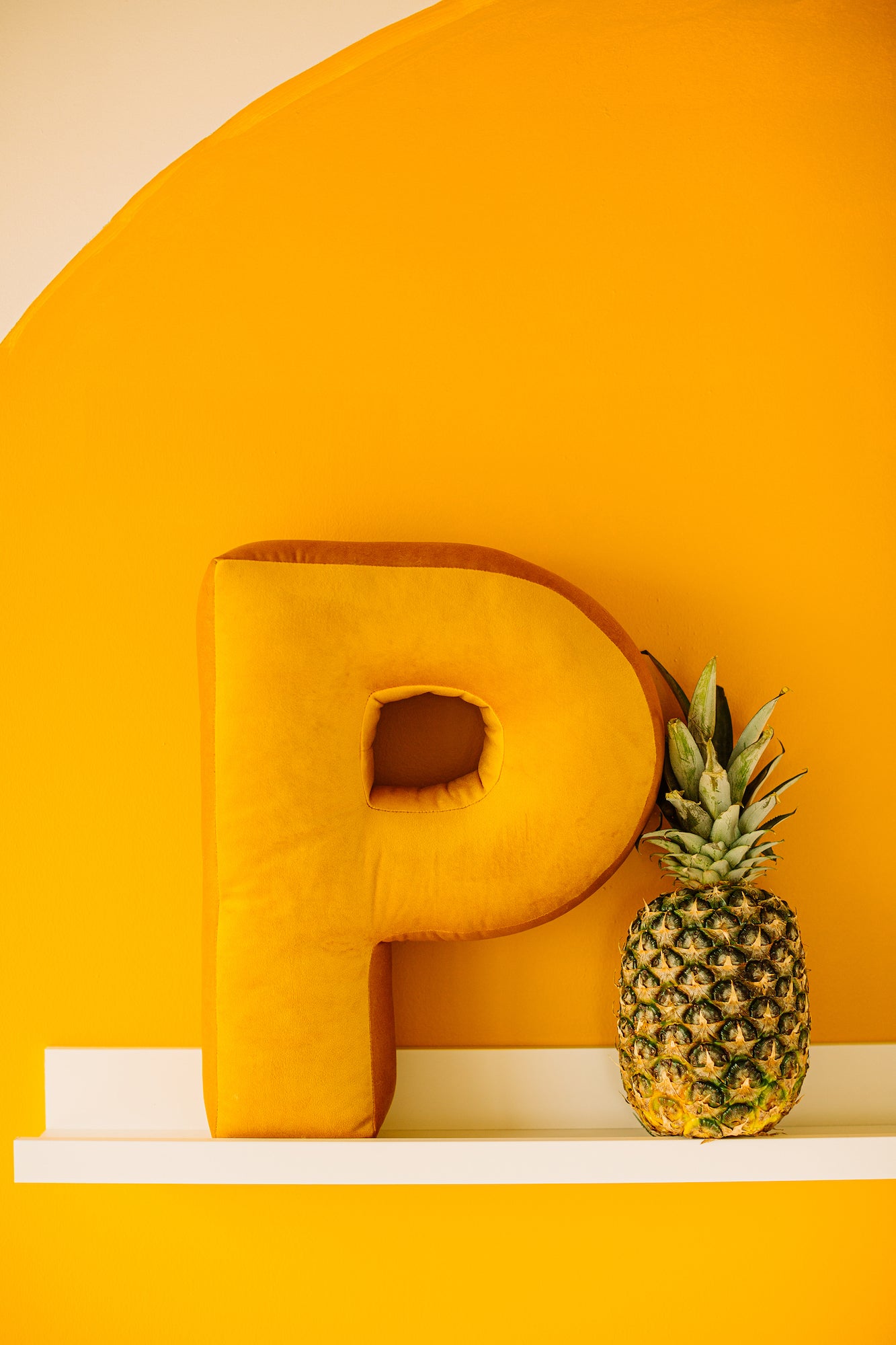 yellow wall with shelf and letter pillow p yellow next to pineapple by Bettys home