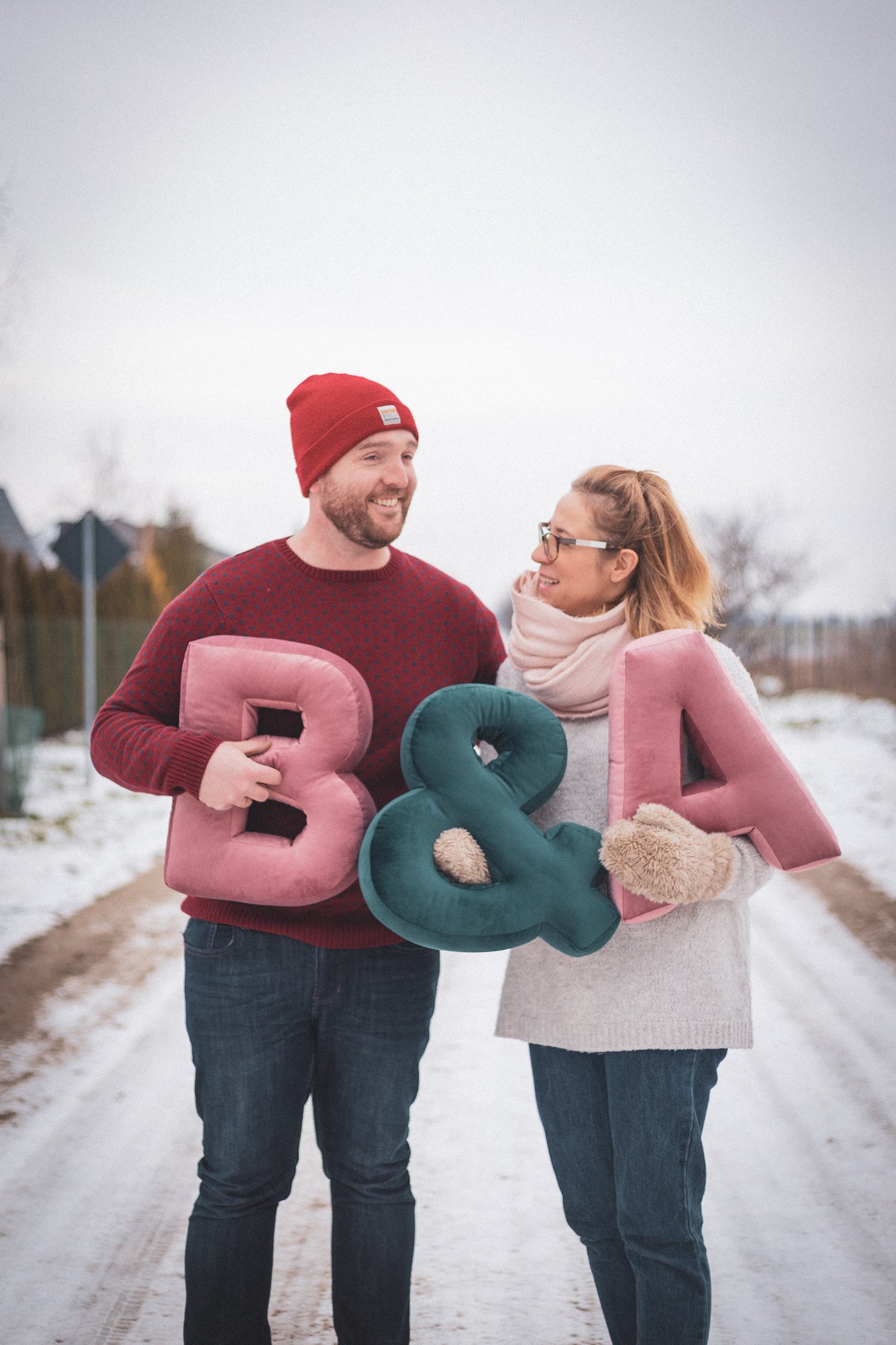 A couple in a winter landscape holds velvet letter cushion. Xmas gift idea for couples. Xmas gift idea for her 