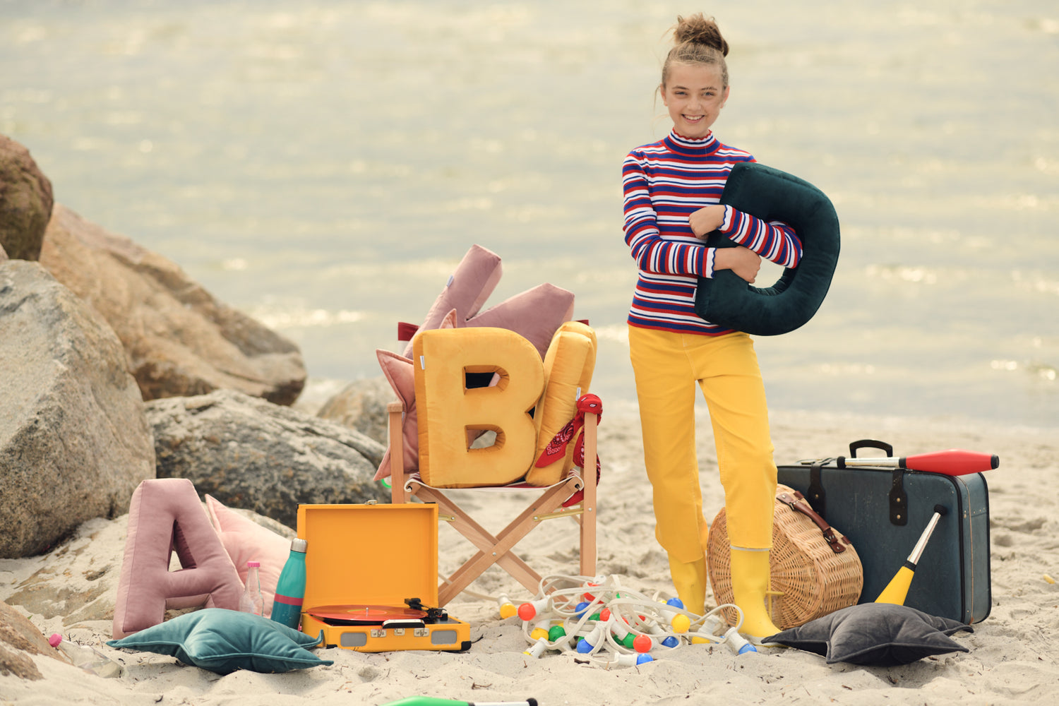 cute girl on beach with few velvet letter cushions by bettys home 