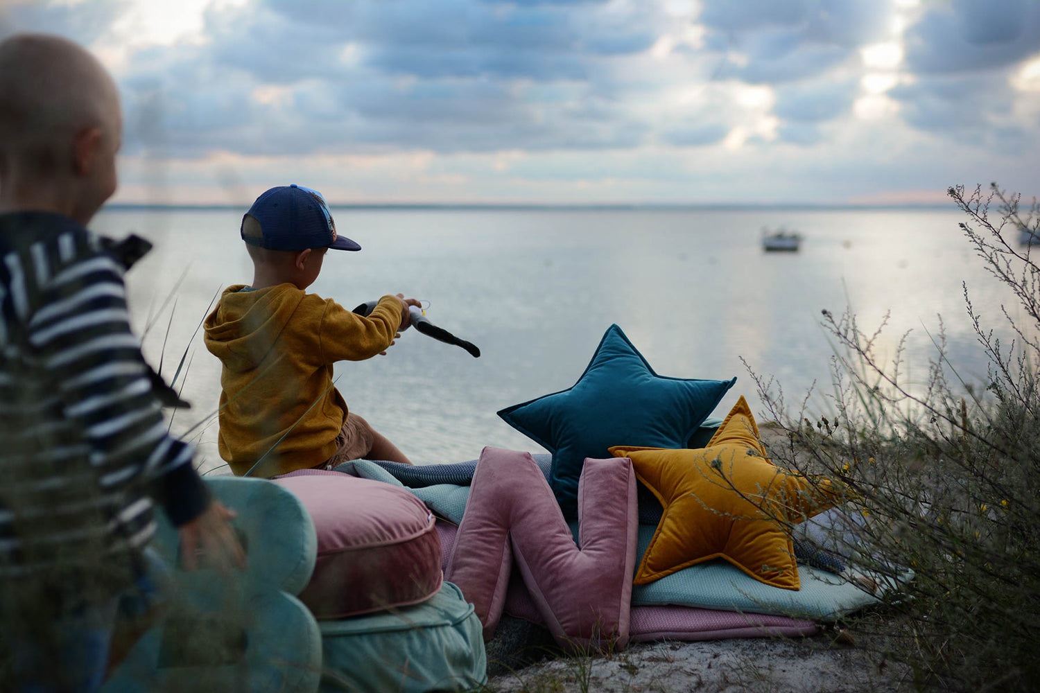 little boy on beach while sunrising with velvet star cushion by bettys home