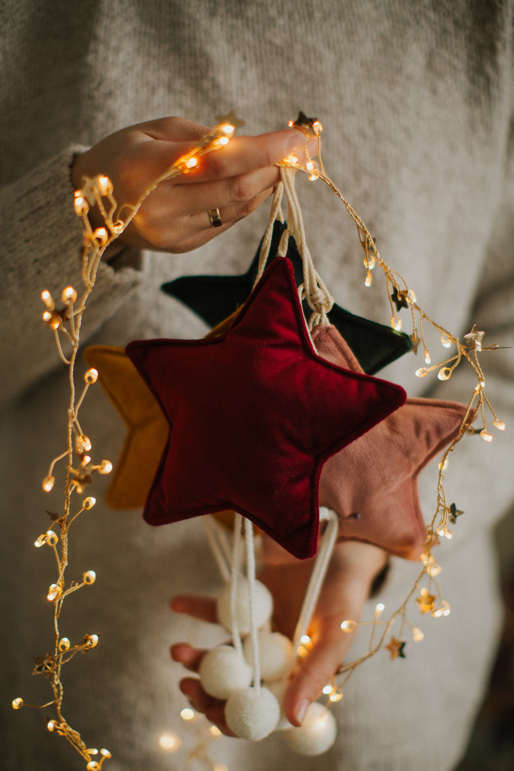 velvet little star pendants wine red by bettys home held by a woman together with Christmas lights