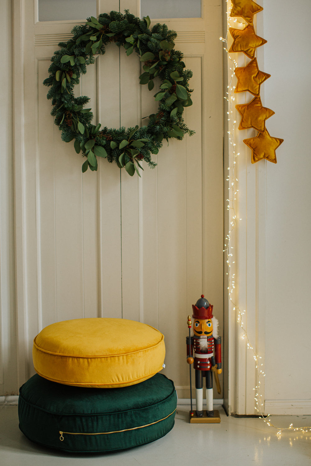 velvet star garland yellow by Bettys home on a door over small velvet pouf and green velvet pouf 