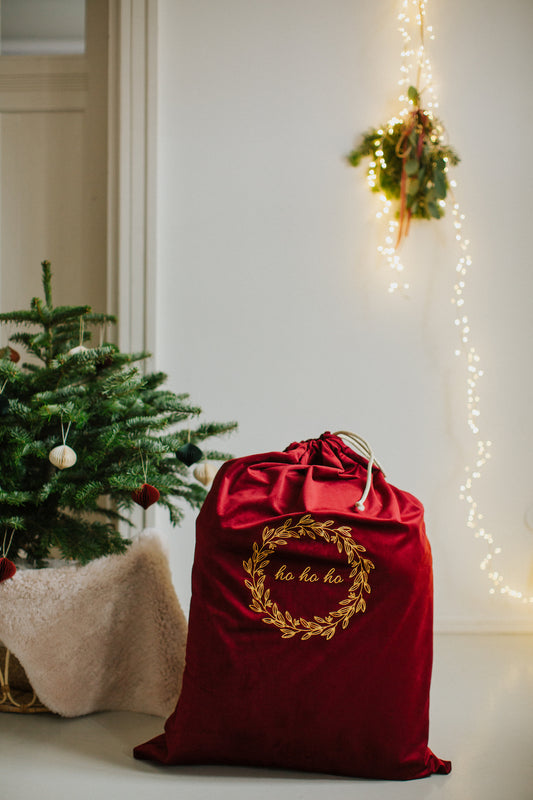 christmas sack in red wine with embroidered ho ho ho by Bettys Home next to christmas tree