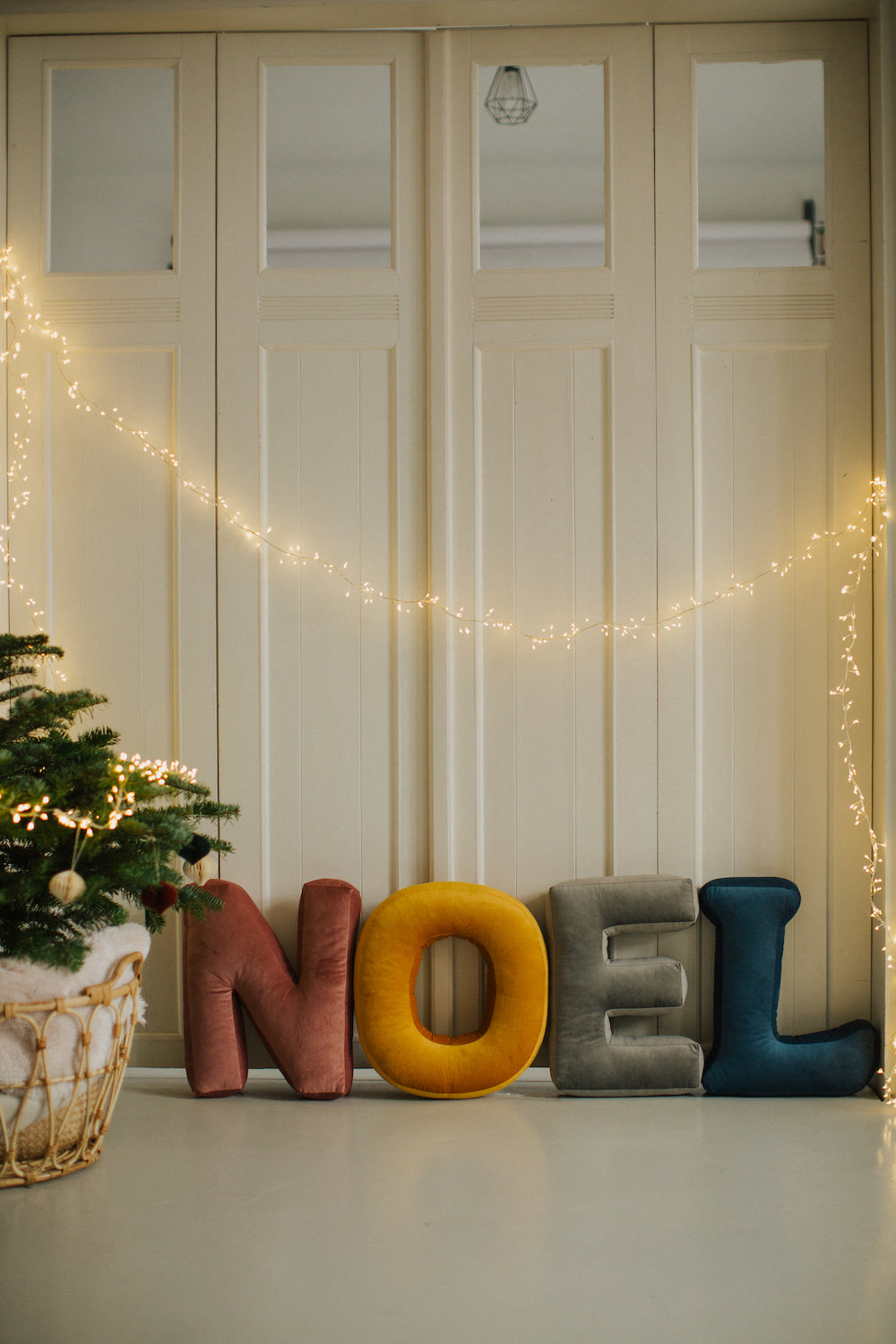 Velvet letter cushions by Bettys Home in word NOEL standing next to christmas tree
